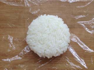 11、米饭汉堡,将煮好的米饭，取一小团放在保鲜膜中，用手捏紧后，再按压成饼状，大小与炸好的肉饼差不多，这样做出两个