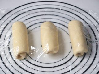 9、淡奶油椰蓉面包卷,将面团擀开卷成圆筒状，3个都做同样处理，盖上保鲜膜静置15分钟左右。