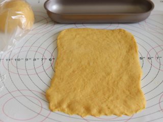 7、胡萝卜热狗面包,做营养美味早餐,取一个,压平,用擀面杖从中间向俩边擀开。整理成和模具差不多宽度的面片,底部压薄,再卷起来,放入模具中。