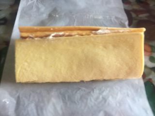 28、黄桃奶油蛋糕卷,蛋糕卷卷口朝下,擀面杖向反方向收拉,用手指伸进油纸底部里面收紧卷口处,放进冰箱里面冷藏定型1小时即可切片食用啦^ ^