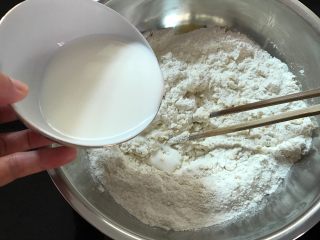 3、奶香石头小面包,慢慢地加入牛奶搅匀。