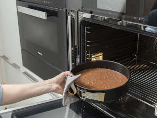 2、黑森林蛋糕,另取一个碗加入糖、香草精和蛋黄,搅拌约5至6分钟,直到变成轻薄蓬松的质地。混合面粉、淀粉、可可粉和泡打粉,过筛加入蛋黄中。搅拌均匀,分两批小心地拌入打发的蛋白。开中低火,在小锅中加热黄油至融化,倒入面糊中并搅拌均匀。将面糊倒入准备好的脱底烤模中,在预热好的烤箱中烘烤约25-30分钟,或用牙签插入蛋糕再抽出,牙签上不沾任何痕迹,即说明烤好。从烤箱中取出,冷却约15分钟后脱模,然后放至完全冷却。