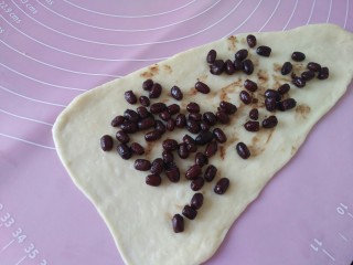 11、最爱面包+蜜豆面包,取一个面团擀成长三角状,铺匀蜜豆