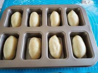 8、炼奶小土司,用擀面杖排气，擀卷成长条形放入模具里面。