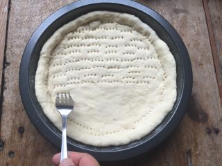 8、双酱培根披萨,用擀面杖将发酵好的面团擀成跟模具差不多大小的形状，放入模具内，让面团完全贴合四周；用叉子在面团上叉一些小孔，避免面团在烤的时候鼓起来；