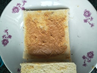 3、懒人料理西多士,其中一片涂上花生酱后将另一片放上。