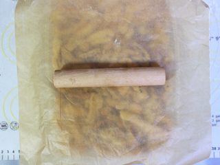 14、沙琪玛,翻拌好后 倒入到四方形的模具内,模具事先内部涂好油,方便脱模,然后在沙琪玛表面盖上一张油纸,用擀面杖 擀平沙琪玛