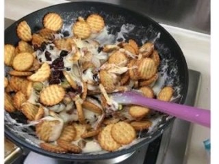 4、开心雪花酥〈快手版〉,先加入蔓越莓干和开心果,再加入小圆饼,关火搅拌均匀。