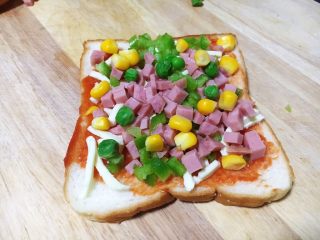8、鲜虾吐司披萨,放入适量的火腿粒、豌豆、玉米。