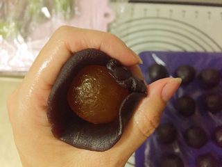 8、蛋黄千层酥,取一个豆沙馅按扁包入一个蛋黄，用手搓圆。