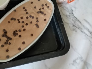 14、古早巧克力豆蛋糕????,将剩下的蛋糕糊倒入模具中，表面撒些可可豆这是一个水浴法的蛋糕，要将蛋糕放入2/3的水中烘烤，可以底下放一个盘子，放入蛋糕模具，然后装满2/3的水