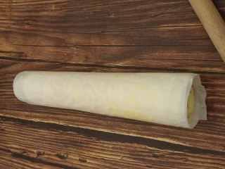 18、虎皮蛋糕卷,借助擀面杖，把蛋糕卷卷起来，这么做蛋糕卷会更加紧实一点。放在一边定型