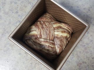 21、大理石纹豆沙吐司,21.两边分别向中间卷，中间漂亮的部分朝上，放在水立方吐司盒中进行发酵。