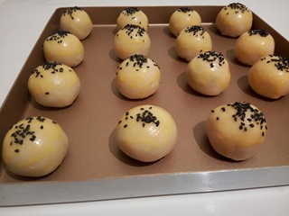 15、#甜味#凤梨蛋黄酥,揉圆，放不粘盘，刷上鸡蛋液，撒黑芝麻
