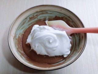 10、圣诞老人可可草莓杯子蛋糕,取三分之一的蛋白霜加入蛋黄糊中，翻拌手法直至看不到蛋白霜。再取三分之一的蛋白霜加入蛋黄糊中，继续上面的手法，翻拌直至看不到蛋白霜。