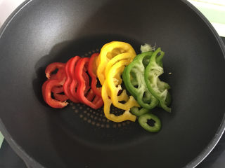 3、美味的牛排披萨,将青椒,红椒,黄椒放入加热的锅中。