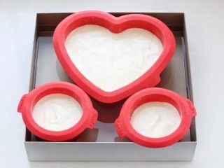 7、酸奶芝士蛋糕,模具底部和周围涂抹少许黄油防粘，将面糊倒入模具中八分满，我用了一个六寸心形模具和两个两寸圆模。取一个深烤盘注入可以达到模具2/3处的温水，把模具放进去。