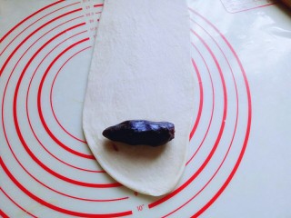 13、#甜味#毛毛虫豆沙面包,取一块松弛好的面团，用擀面杖擀成长舌状，再把豆沙馅放上去。(也可以把豆沙馅压扁，和面团一起擀成长舌状，根据个人喜欢来。)