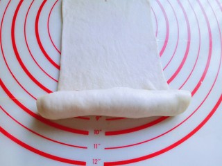 14、#甜味#毛毛虫豆沙面包,再长舌状面皮的另一端从下往上卷起来，卷到一半时停下来，如图。