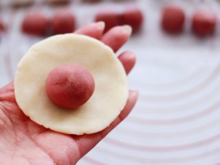 8、桃花朵朵开-桃花酥,这个时候取一个水油皮按扁，擀圆，包入一个油酥。