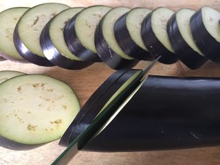 4、鲜虾茄盒,长茄子洗干净,斜刀30度切片,每片约1厘米厚,第一刀切下后,底部留1厘米左右不要切断,第二刀切断,形成一个茄盒,貌似蚌壳那样尾部时连接的。