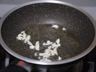 7、酱爆鱿鱼圈,锅子清理干净再次放入油烧热,爆香蒜末