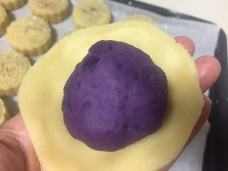4、广式月饼（紫薯蛋黄馅）,醒好的月饼皮面团称重分成40克一个的小剂子，取一个小剂子捏成圆片紫薯蛋黄放在面皮中间