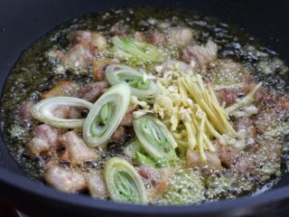 5、豆角焖面,然后放入葱花、蒜末和姜丝炒出香味来