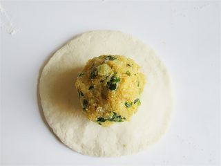 12、玉米馅葱香饼,将小剂子擀成中心厚边缘薄的大面片，放入玉米面团做心包成一个馒头