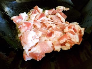 4、炒五花肉,锅内放油烧热，放入肉片翻炒。