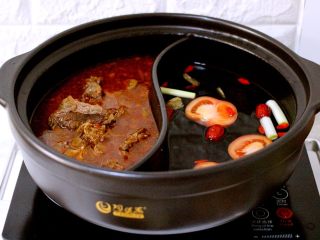 15、什锦海鲜羊蝎子鸳鸯火锅,把做好的羊蝎子倒入鸳鸯锅的一边、另一边加入适量清水、加入切成的番茄、洗净的红枣和枸杞、放入葱段和姜片