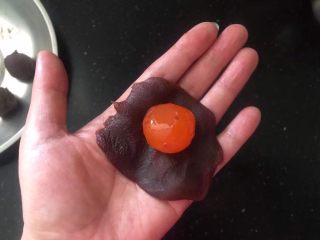 5、蛋黄酥,取一份红豆沙拍扁，放入一个咸蛋黄。