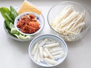 1、部队火锅,韩式年糕掰开清洗两遍浸泡在水中，金针菇和油菜洗净，准备好辣白菜和芝士片。