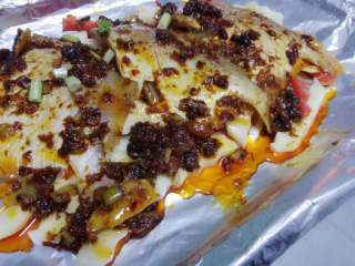 6、烤鲳鱼,烤盘放一层锡箔纸，底层放入配菜再倒入一层调料汁，放入鲳鱼，再涂抹一层盆中的调料汁（剩余的调料汁留着备用），最后表面均匀刷一层香油。