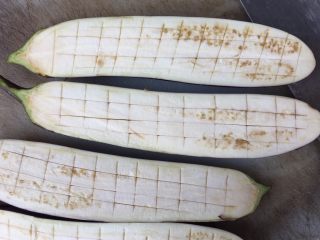 2、意式肉酱烤茄子,先将茄子洗净后切成两半,再用刀将茄子划上几刀
