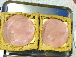 7、爆浆吐司托蛋,再铺上一张火腿，再次往下压一压。