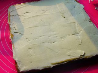 19、抹茶漩涡蛋糕,19．	把打好的奶油抹在蛋糕片上，奶油的厚度最好是要均匀。