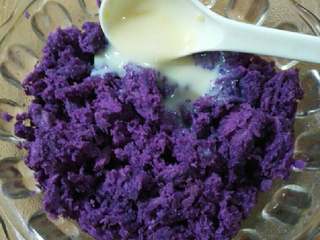 3、水晶南瓜饼,趁热把紫薯装入碗中，用勺子压成泥，加入一勺炼奶搅拌均匀。