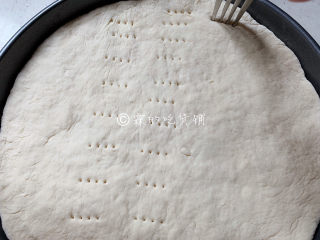 11、冬至美食 培根蘑菇披萨,用擀面杖,把发酵好的面团擀圆,放入披萨盘中,再用叉子在面皮上扎些小洞。