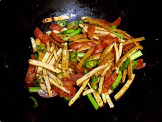 9、腊肠炒香干,放入腊肠片、香干片和杭椒段炒匀。