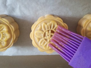 14、蛋黄莲蓉月饼,取出烤盘，在月饼表面刷一层薄薄的蛋黄液，一定要薄。继续放回烤箱，170度烤15分钟。