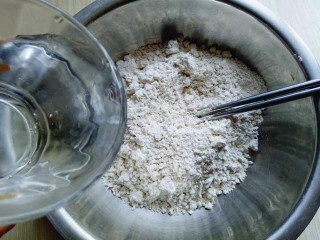 2、凉拌莜面鱼鱼,分次加入开水。（切记不要一下子将开水倒入，不同的面粉吸水性不同，一定要分次加入开水）