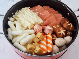 7、部队火锅,再依次摆放入火腿肠、芝士年糕、香菇、海鲜丸子,金针菇
