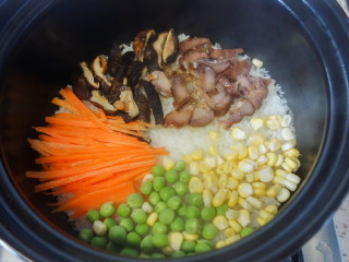 6、超简单又好吃的彩虹煲仔饭,6、	胡萝卜丝、青豆、玉米粒摆在米饭上，中间留出一个洞