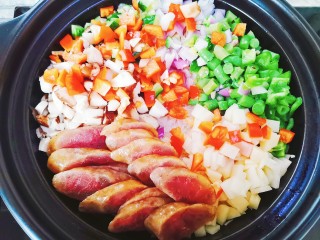 6、腊肠煲仔饭,把腊肠和蔬菜铺在米饭上