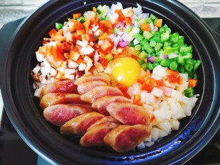 8、腊肠煲仔饭,开盖打入一颗鸡蛋,顺着锅边淋入食用油