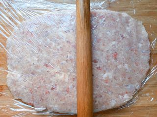 11、温州+正宗温州鱼饼,在案板上铺上保鲜膜，将抓捏均匀的鱼泥放在保鲜膜上，上面再盖上一张保鲜膜，然后用擀面杖反复敲打，敲打至很柔韧的鱼肉泥。（需要20分钟左右）