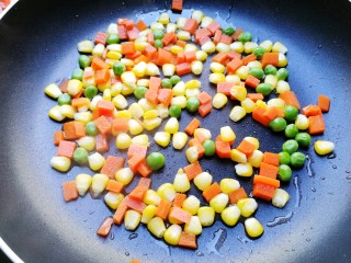 11、菠萝炒饭,锅里放少许油，放入煮好的豌豆仁、玉米粒和红萝卜丁，翻炒一下