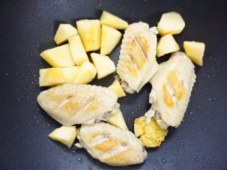 6、鹰嘴豆焖鸡翅,鸡翅煎好一面后，翻面，再把苹果也一齐放入煎香一下。