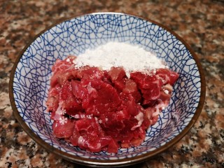 4、杏鲍菇炒牛肉,将牛肉切成片并加入适量淀粉、清水和花椒油拌匀。